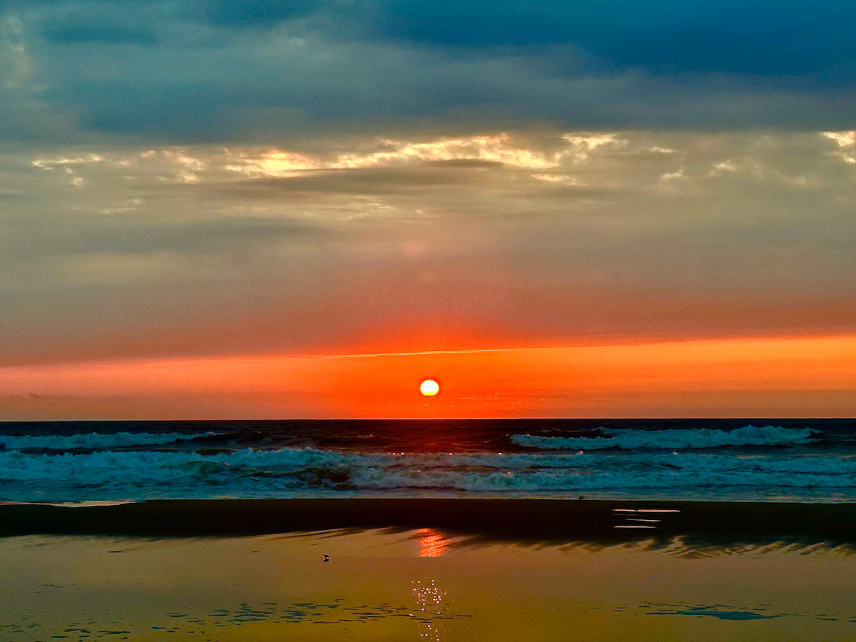 Sun dropping into the Atlantic in bands of red and teal