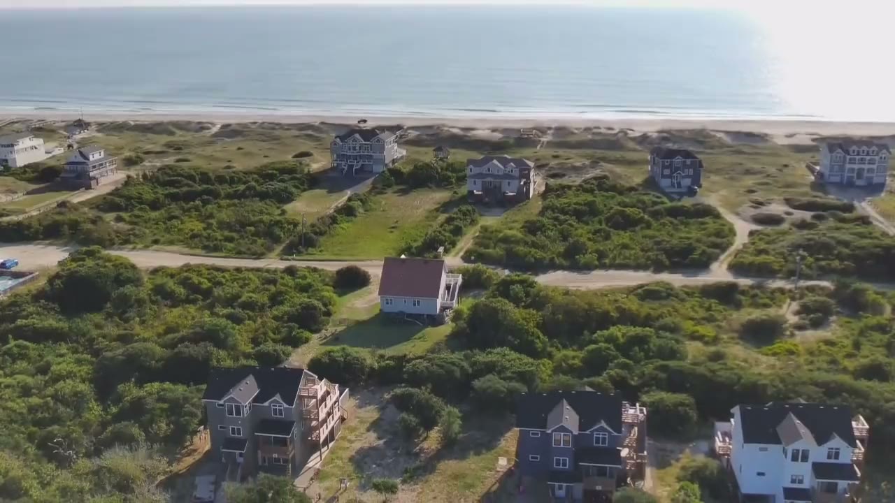 Drone footage drifting over the dunes and houses of Carova Beach with the Atlantic beyond